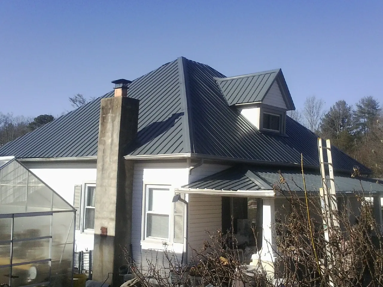 Dark blue standing seam metal roof on a white farmhouse with dormer — Slate & Tile Roof Repair by Roofing Brothers in Barbourville