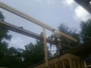 Carpenter setting a ridge beam over a new addition frame — Ice Dam Removal by Roofing Brothers in Barbourville