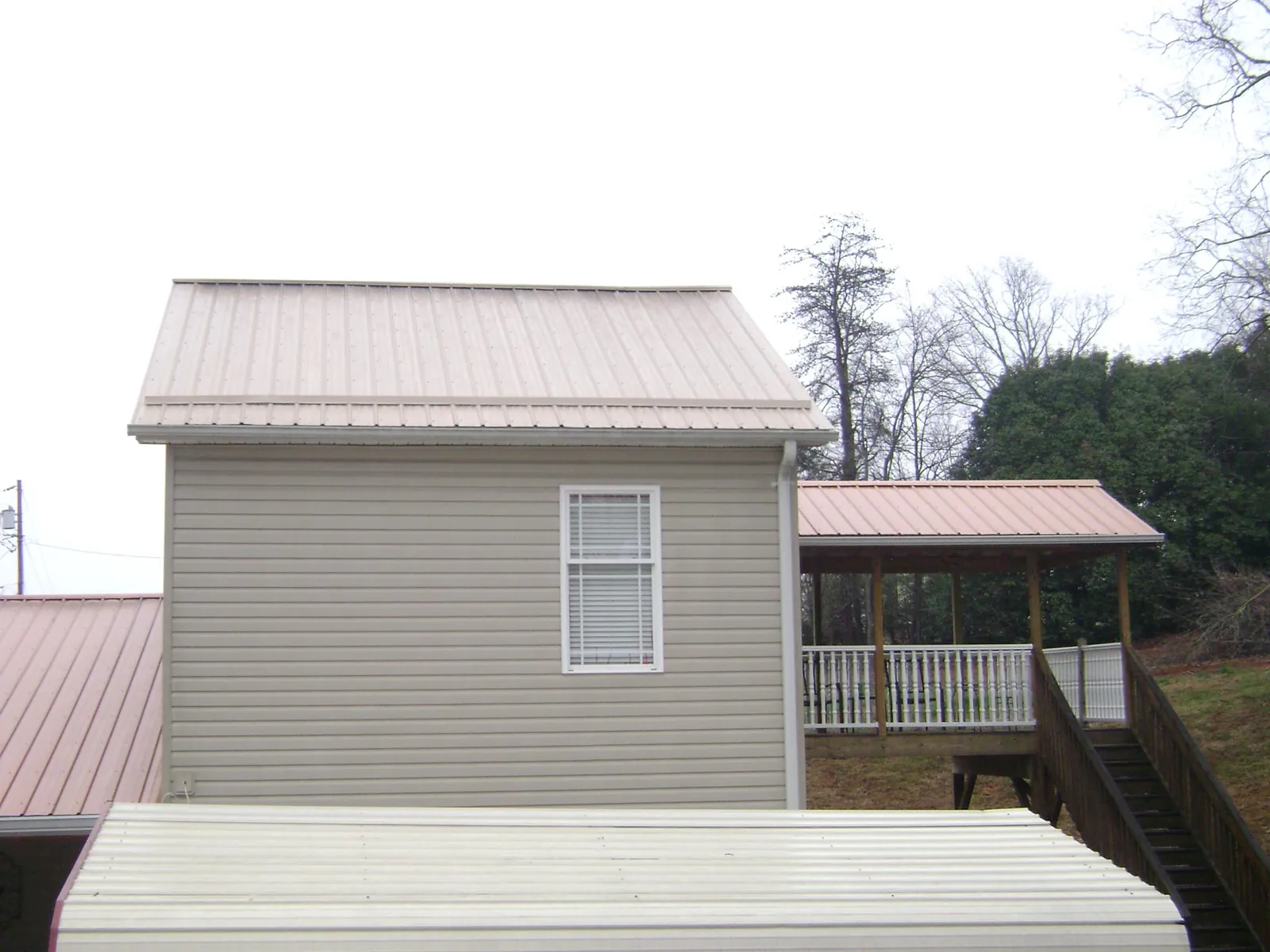 Tan metal roofs on a two story addition and attached porch, from a Roof Replacement job in Barbourville