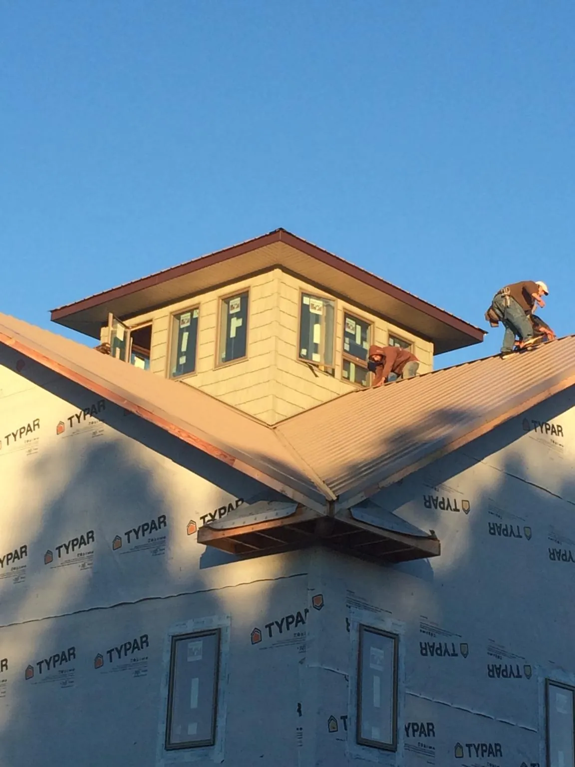 Roofers working around a rooftop cupola on a new metal roof at sunset — Roof Waterproofing in Barbourville by Roofing Brothers